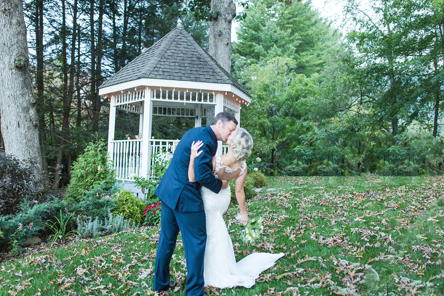 Groom dipping the bride and giving her a kiss in front of a gazebo