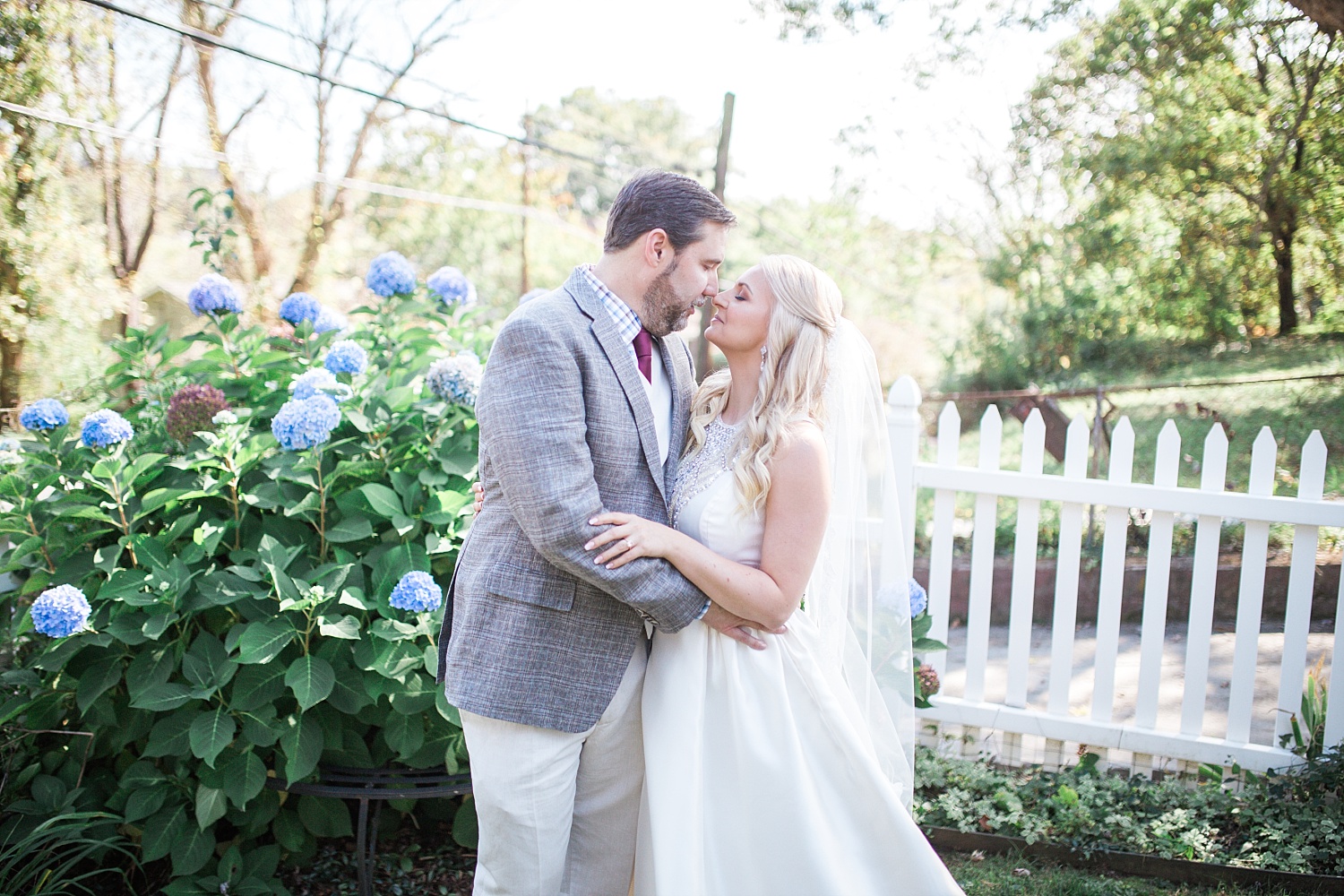 Bride and Groom kissing in front of purple bush