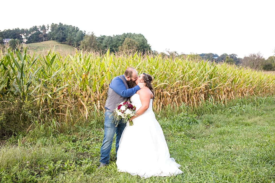 Bride and groom kissing in a hayfield