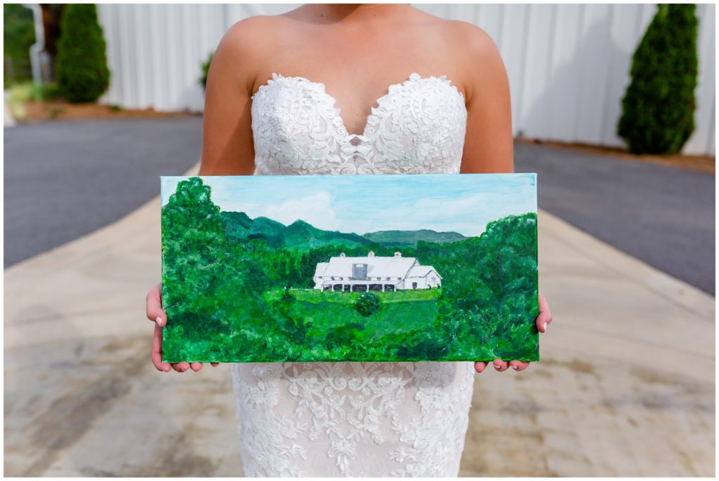 Bride with a hand painted canvas painting of her wedding venue, Chestnut Ridge