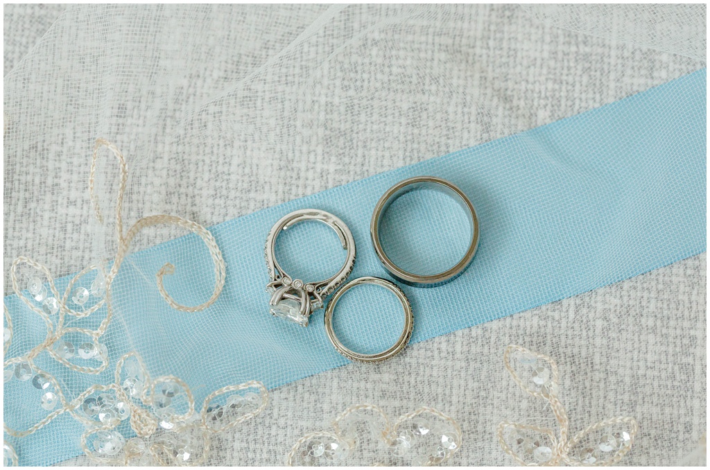 wedding bands and engagement ring laying a top a blue ribbon to match her bouquet accessories