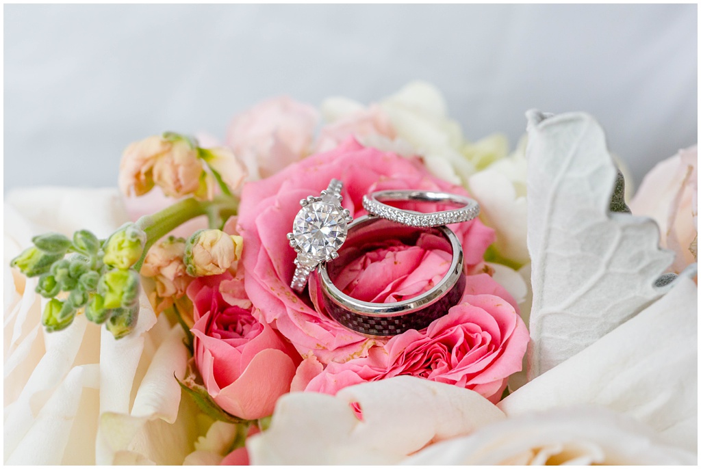 wedding bands and engagement ring on bridal bouquet
