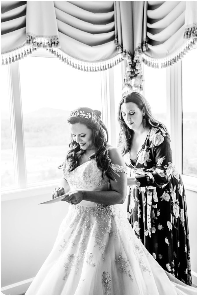 Black and white image of the bride getting in her gown