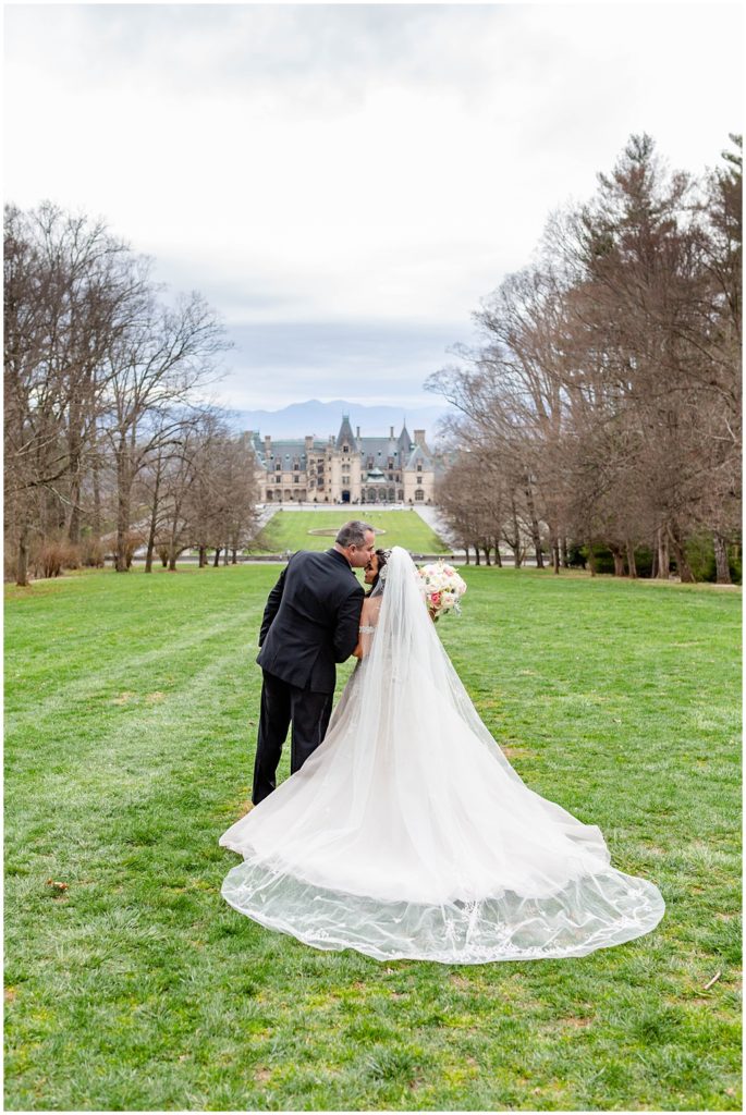 Bride and groom spring wedding portraits on the hill with views of the Biltmore Estate