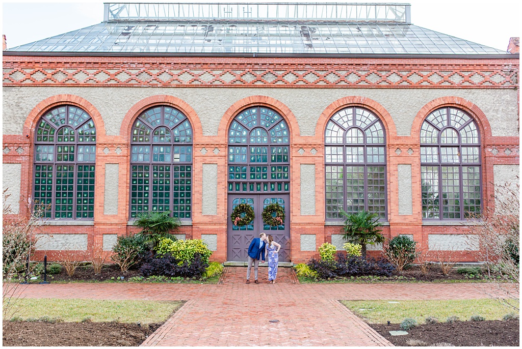 Wide shot of couple kissing outside the Biltmore estate greenhouse