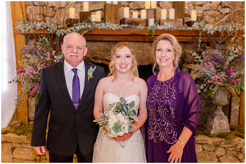 A photo of the bride with her mom and dad dressed in purple.
