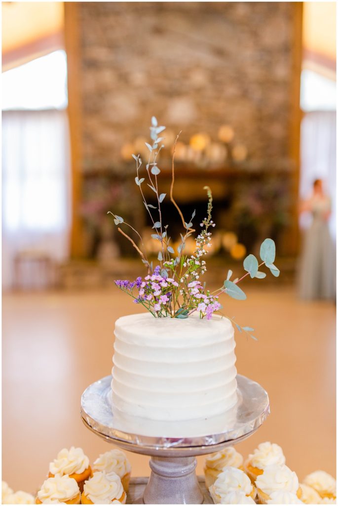 Single tier wedding cake with florals coming out of the top.