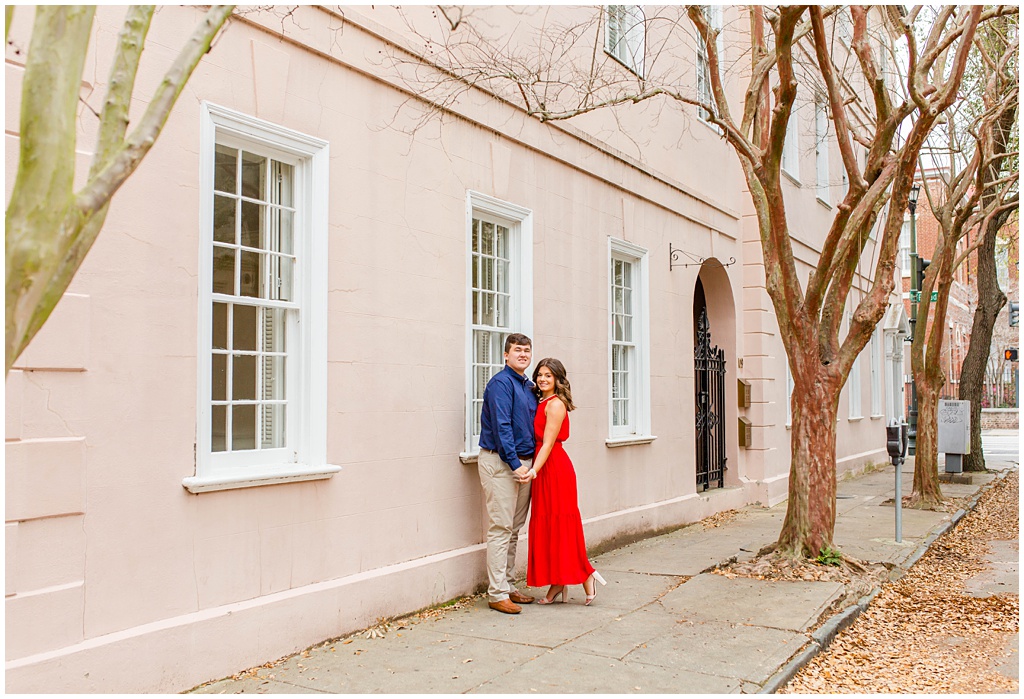 Engagement photos in downtown Charleston along a pink wall.