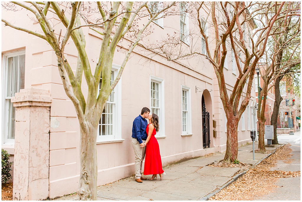 Engagement photos in downtown Charleston along a pink wall.