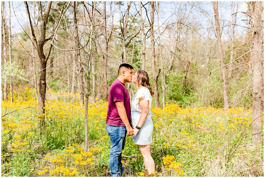 Couple kissing in a field of yellow wildflowers.