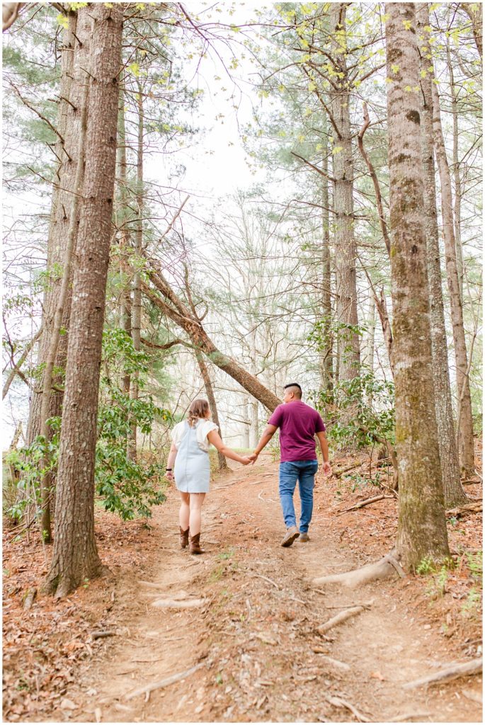 Couple walking through the woods at Taylor Ranch holding hands.