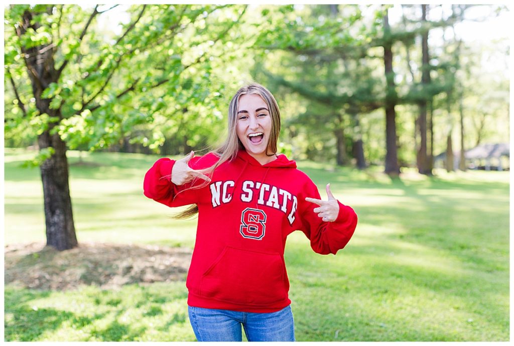 Chloe pointing at her new NC State University sweatshirt with excitement.