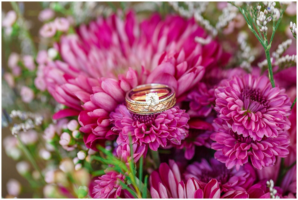Gold weddings rings laying on purple flowers from the bride's bouquet.