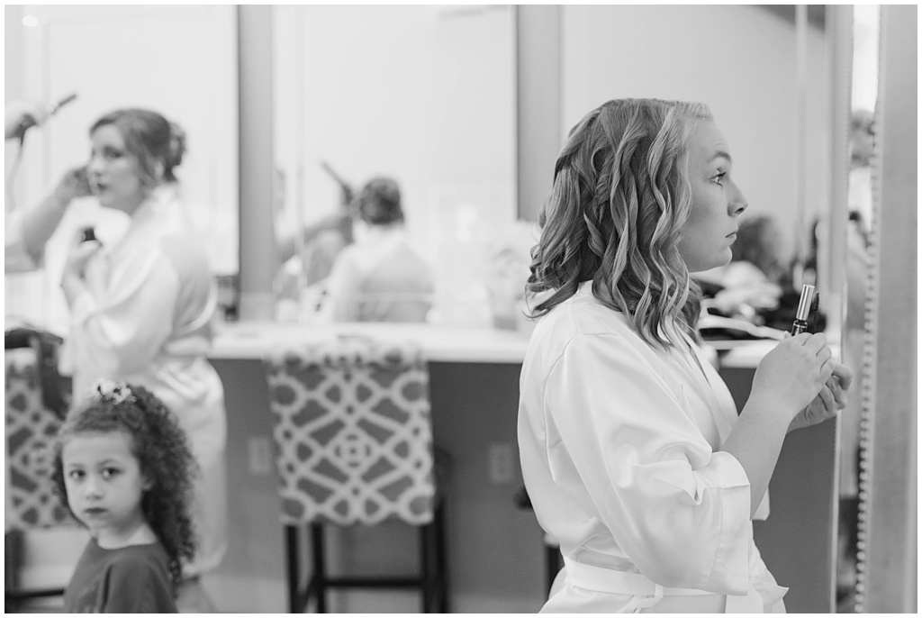 Black and white image of the bride putting on mascara.