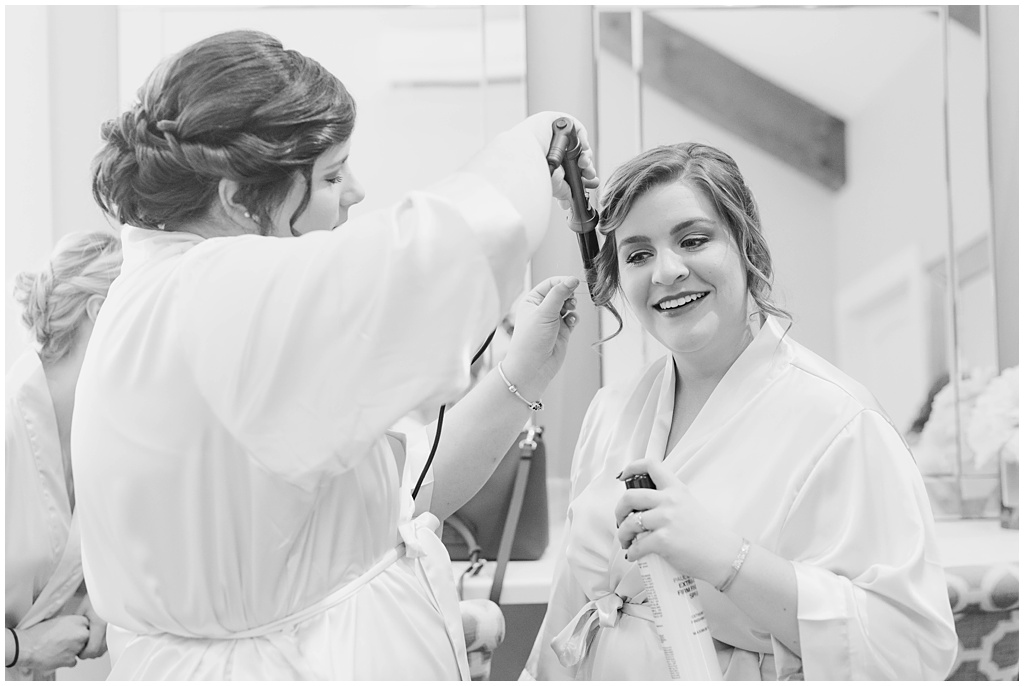 Black and white image of the bridesmaids curling each others hair.
