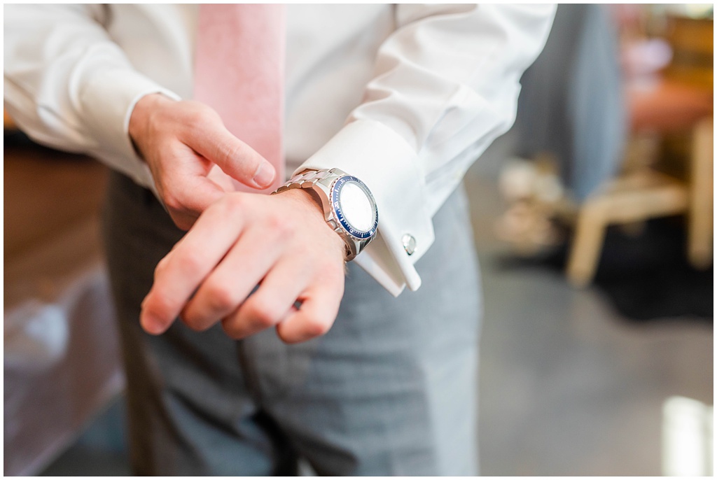 The groom puts on a silver watch.
