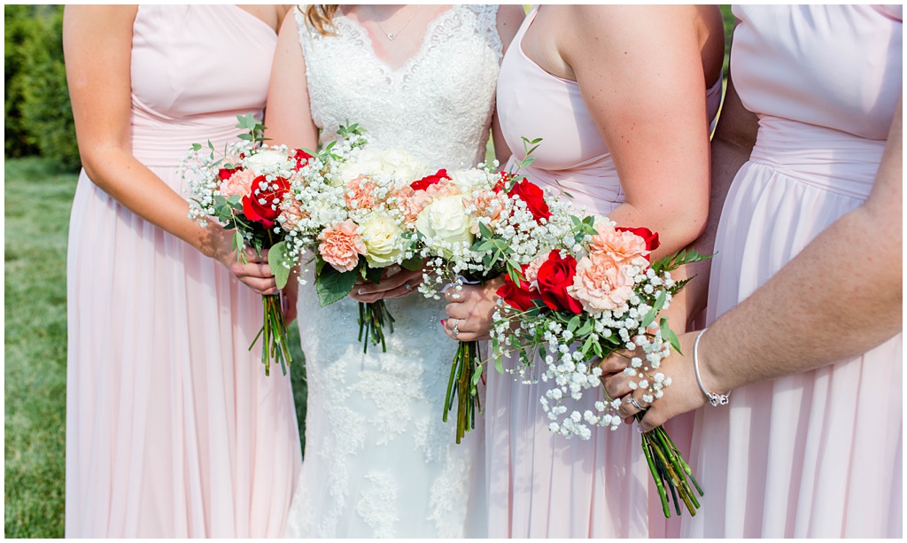 Close up photo fo the pink and red bridal bouquets made of roses, carnations, and baby's breath.