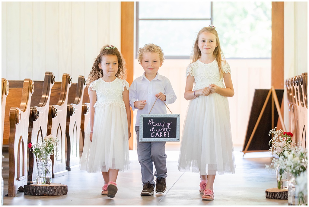The ring bearer and two flower girls walk down the aisle together.