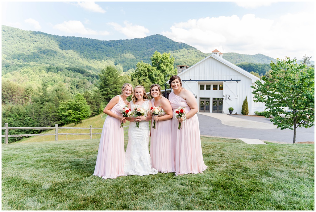 The bride and her bridesmaids together on top of a hill at Chestnut Ridge with Mountains in the background.