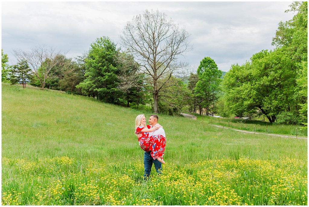 Matthew carries Mary through a field of yellow wildflowers during their Asheville engagement session.