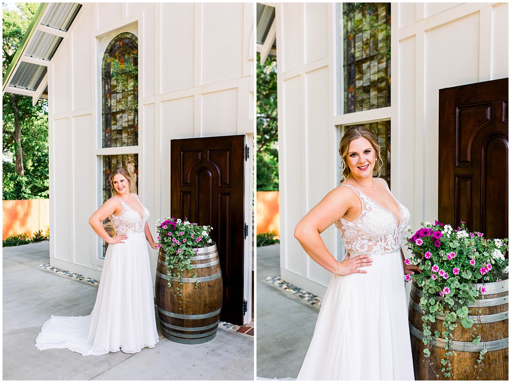 The bride stands next to a wooden barrel in front of the chapel with purple flowers.