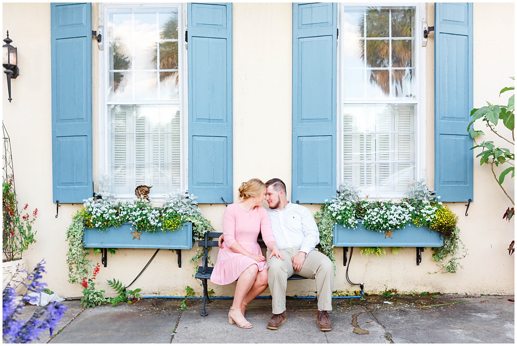 Downtown Charleston Spring engagement photo sitting on a bench with flower boxes.