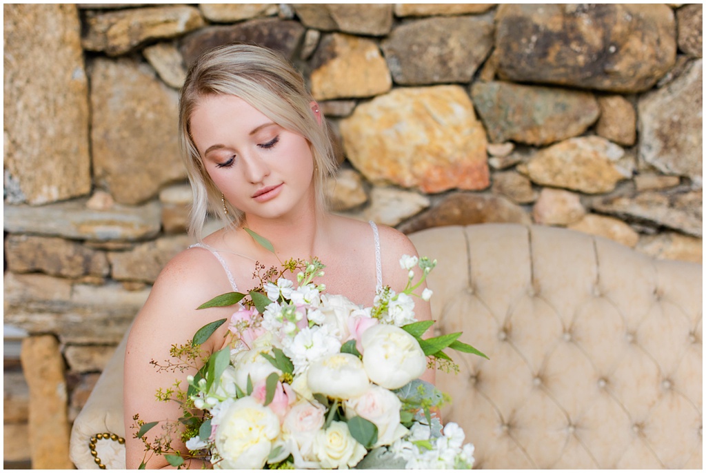Bride sitting on a vintage couch on a stone patio.