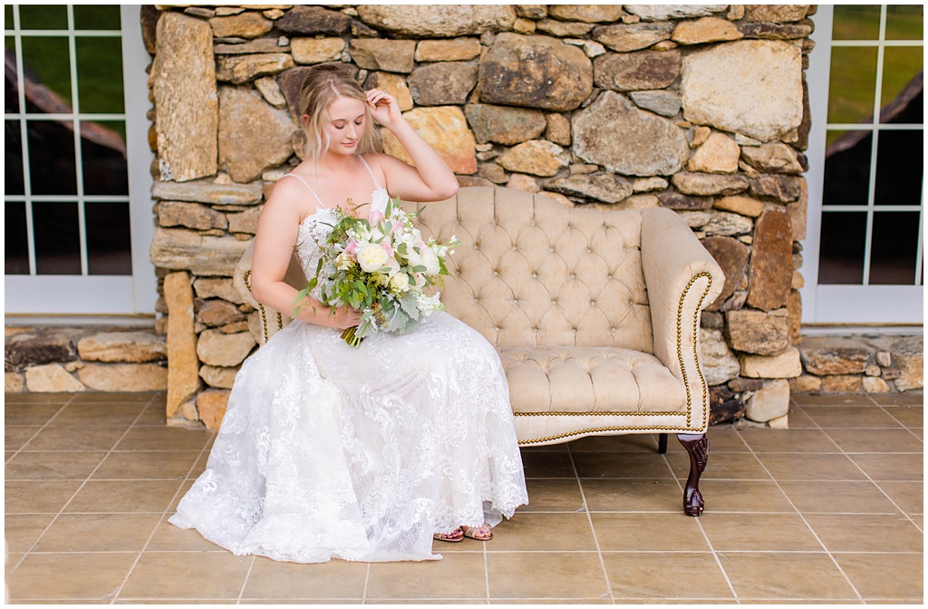 Bridal portrait of a bride sitting on a tan couch on a stone patio.