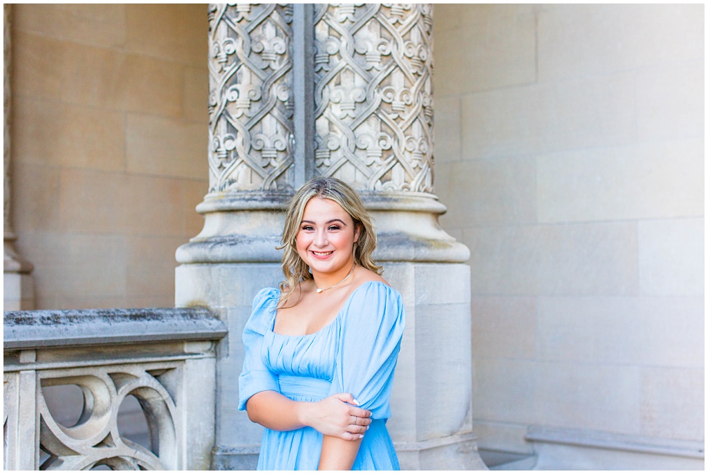 girl in blue boutique dressing smiling in front of columns

