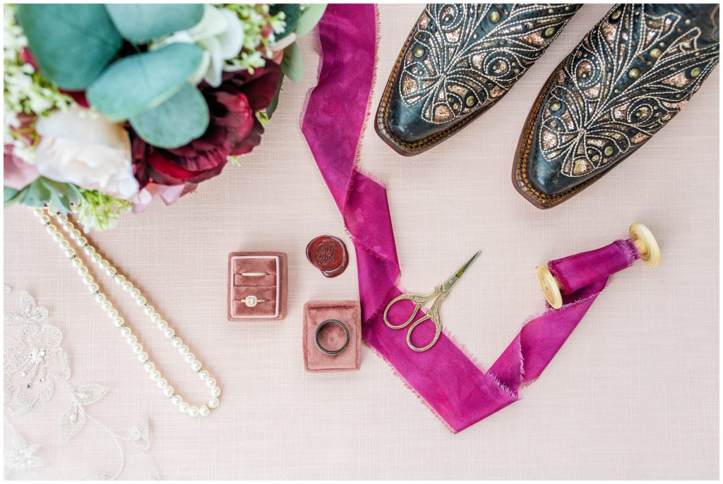 Wedding rings, a pearl necklance, and leather cowgirl boots for the bride.