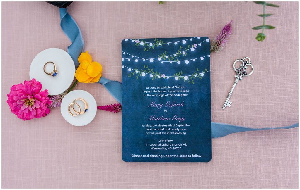 A blue wedding invitation with flowers and rings | Asheville Wedding Photographer