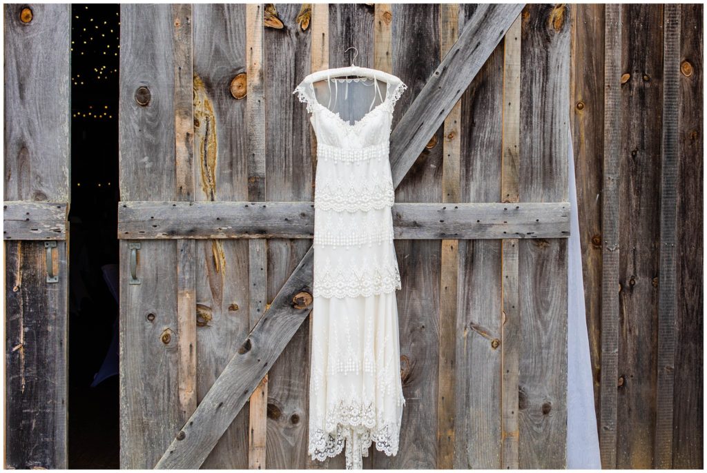 A white lace wedding dress hanging on a barn door | Asheville Wedding Photographer