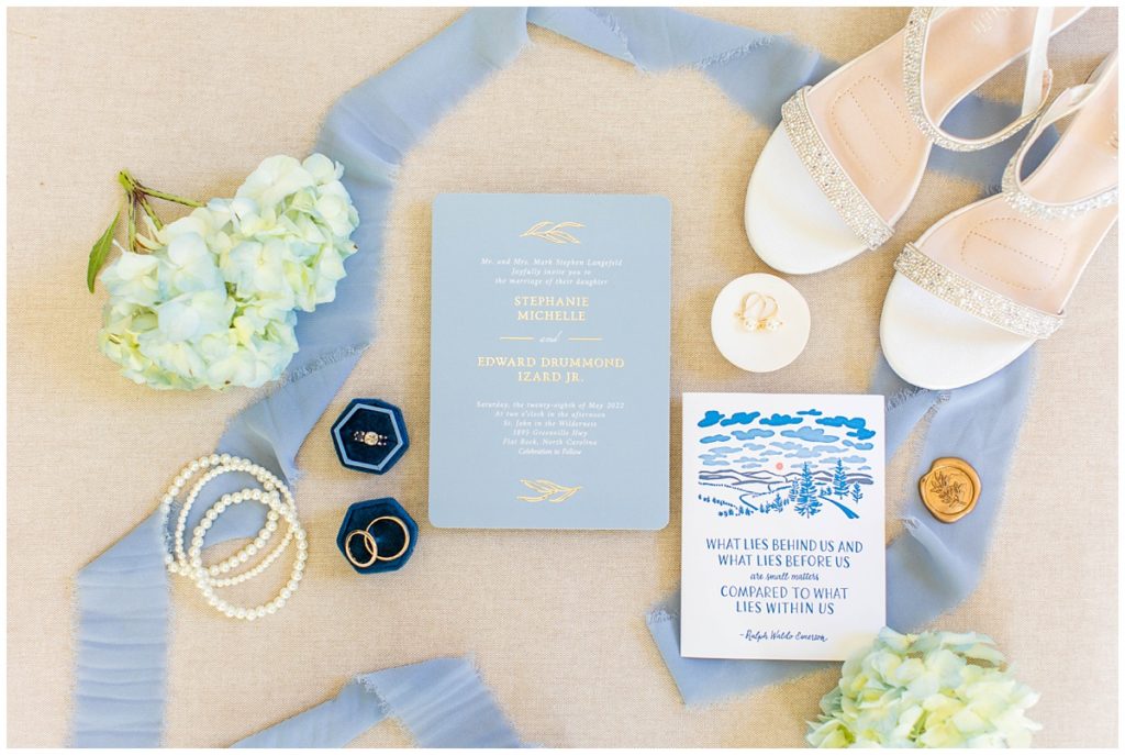 white and blue wedding paper details flat lay with bridal accessories