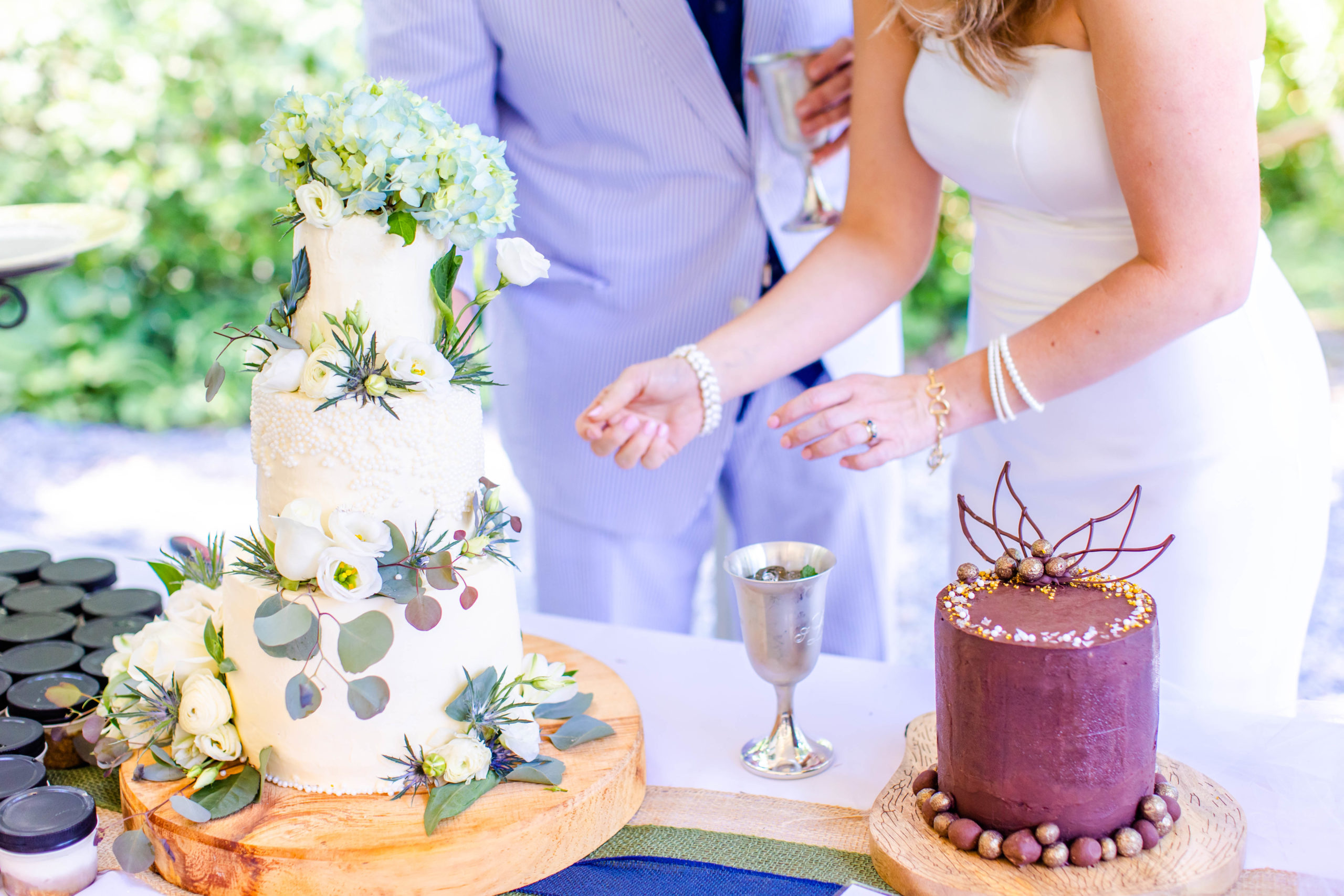 couple cuts the cake at their wedding outside under a tent.