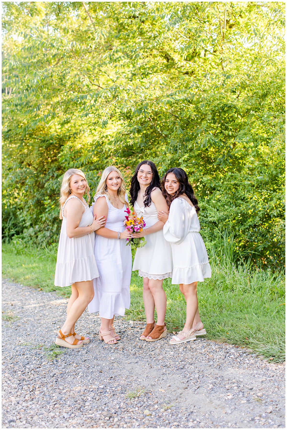 four high school seniors in white dresses doing a photo shoot for their senior portraits