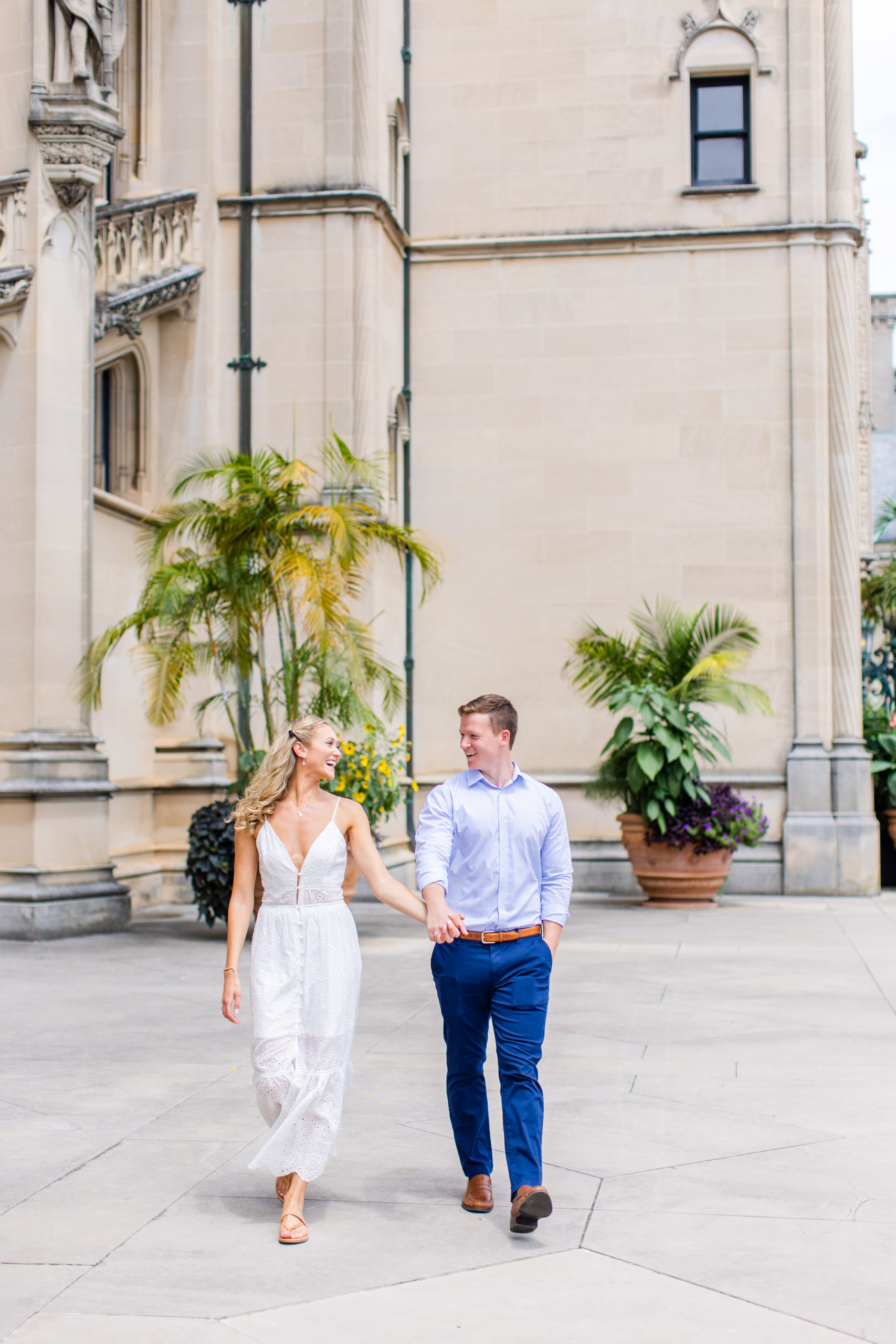 Newly engaged couple walking in front of the Biltmore Estate