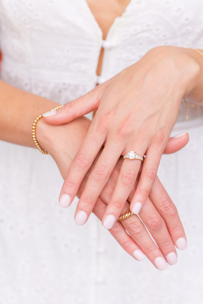 Newly engaged woman shows off her engagement ring on her hand resting on top of her other hand