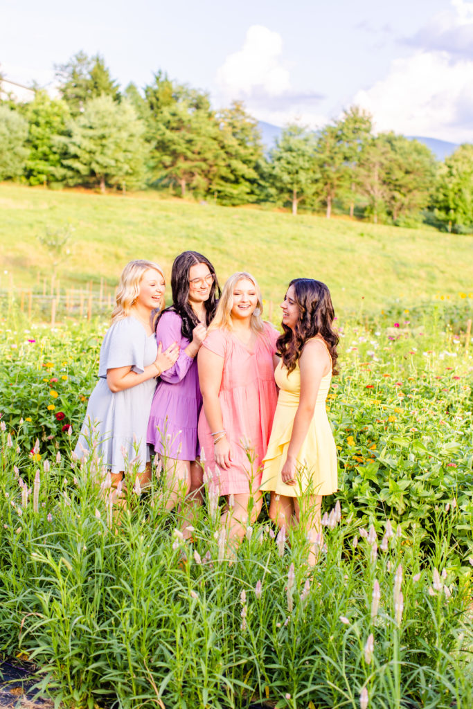 four high school senior girls pose in flower farm for their senior session
