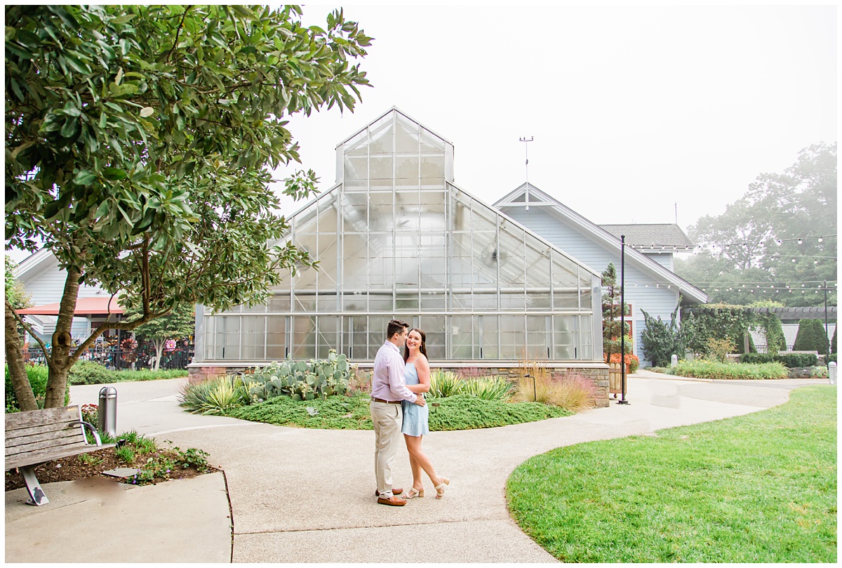 Couple poses outside the greenhouse at the NC Arboretum for their engagement session