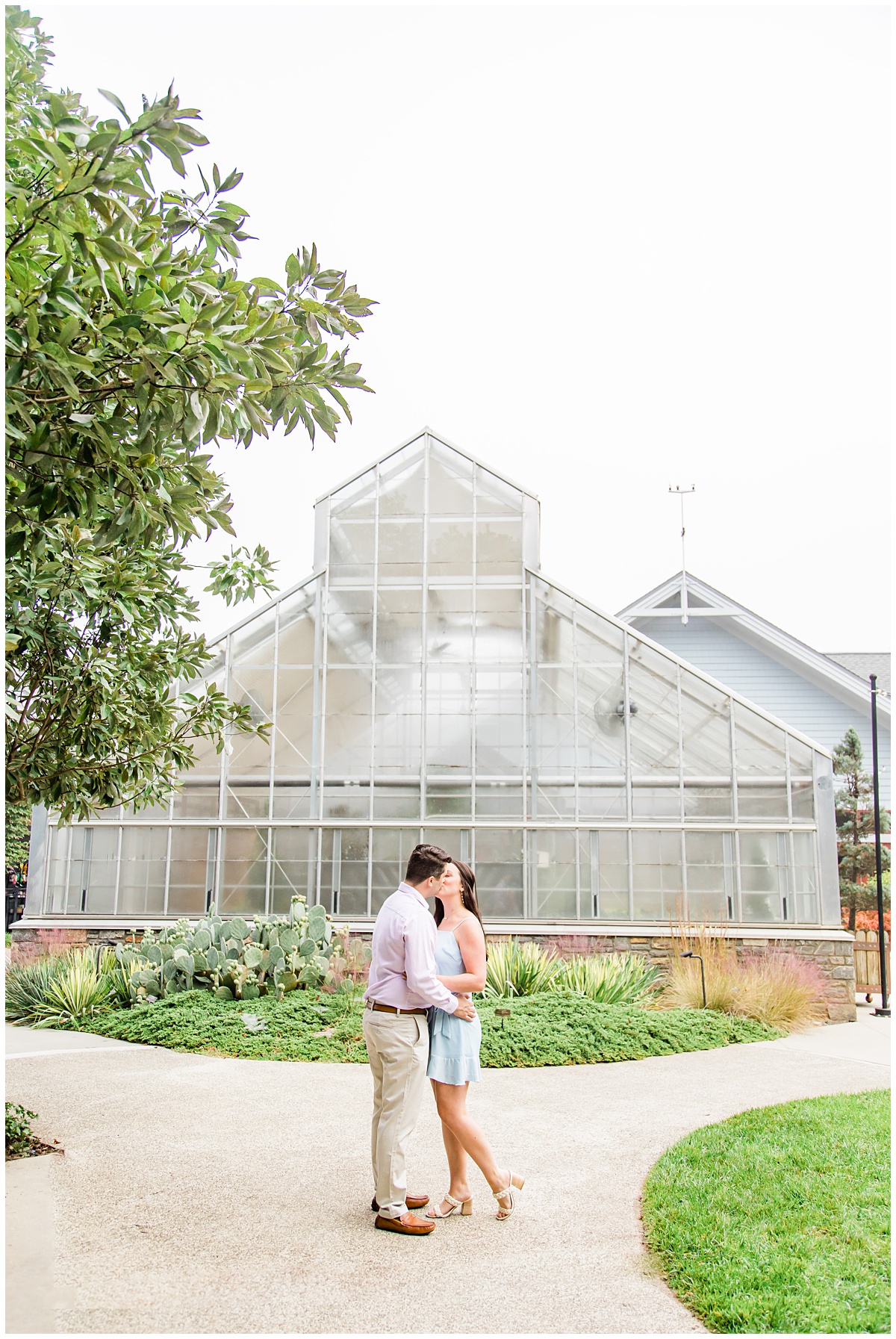Couple poses outside the greenhouse at the NC Arboretum for their engagement session