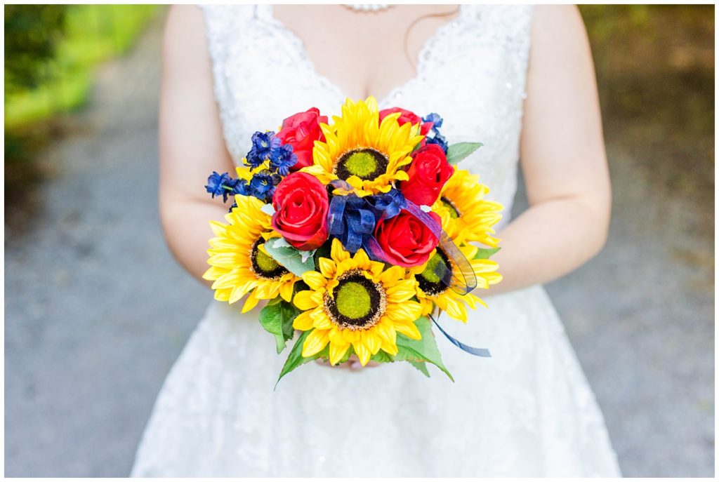 bride holds yellow, red, and blue bouquet