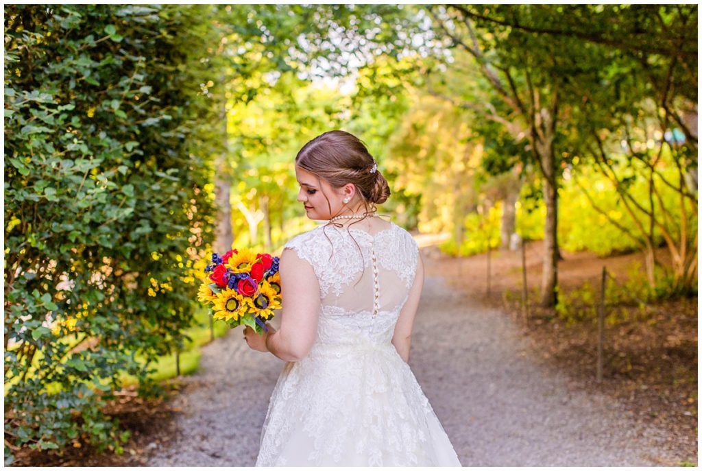bride shows off the back of her dress while holding bouquet