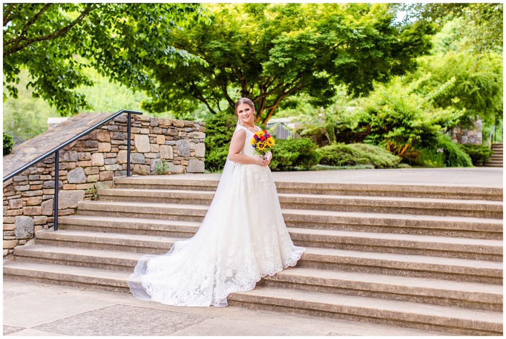bride poses on steps of the NC Arboretum