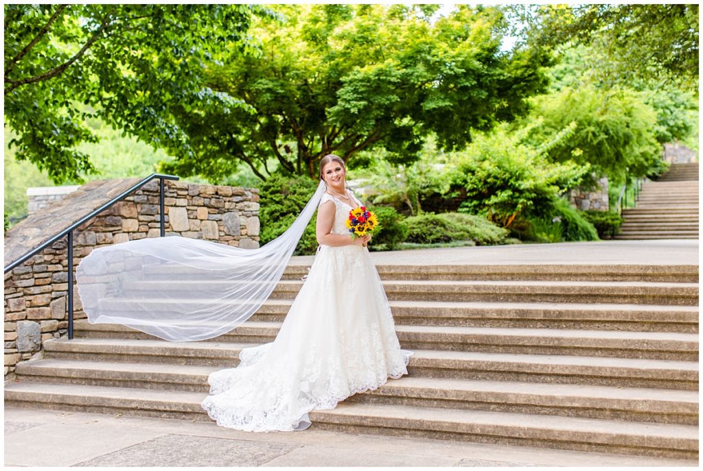 bride poses on steps of the NC Arboretum