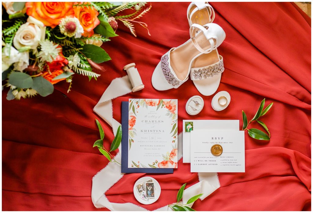 bridal details and invitation suite on red fabric