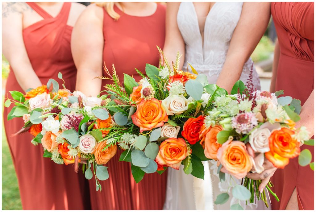 bride and bridesmaids wearing orange dresses holding bouquets
