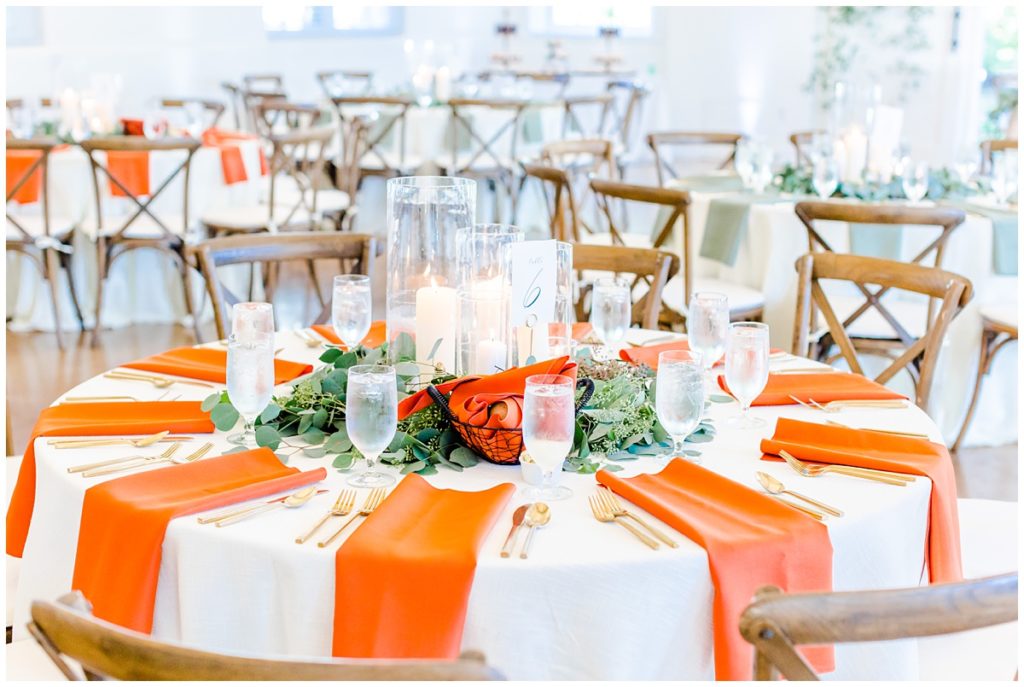 indoor reception space with white linens and orange napkins