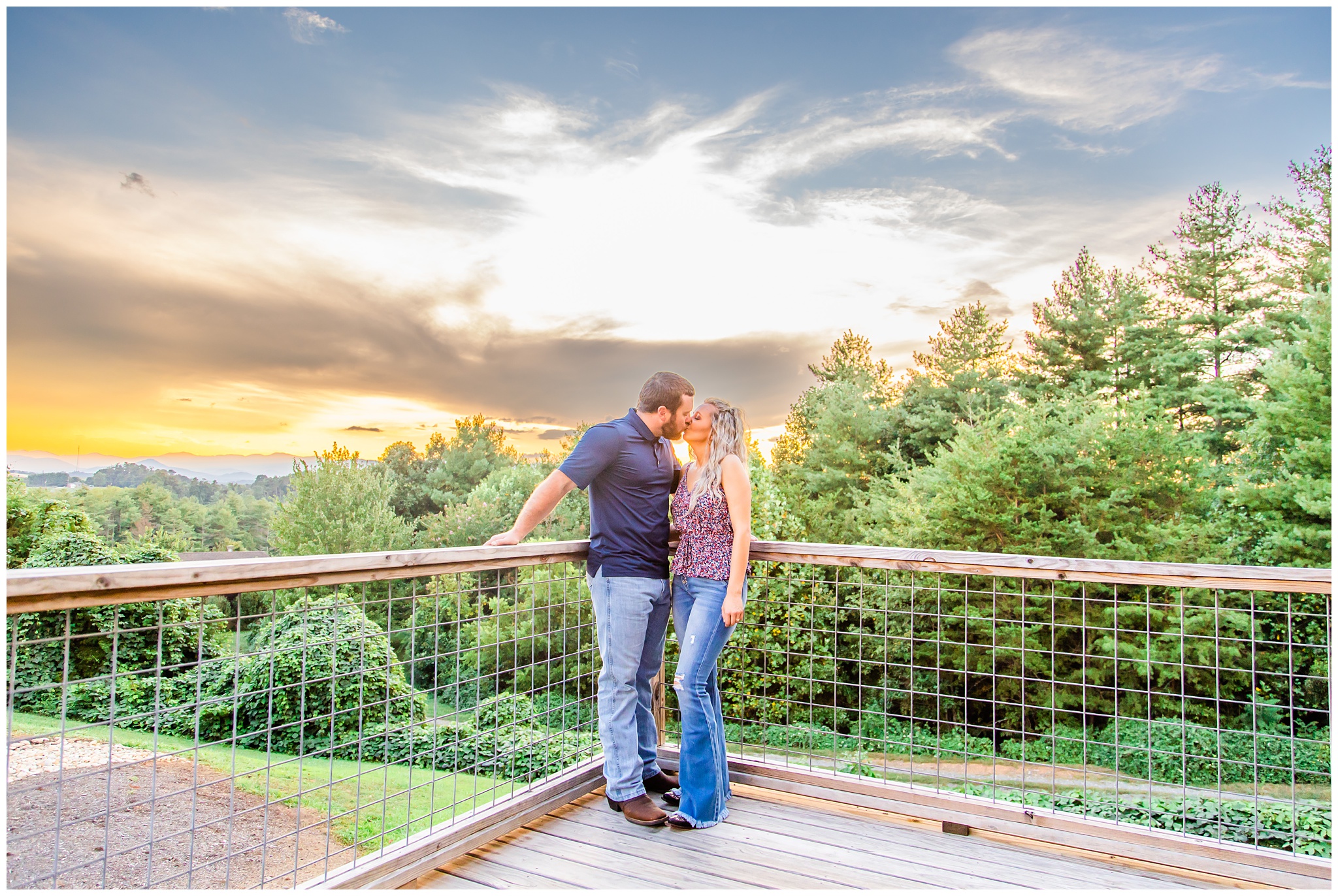 couple kisses on a deck with sunset behind them for their anniversary session