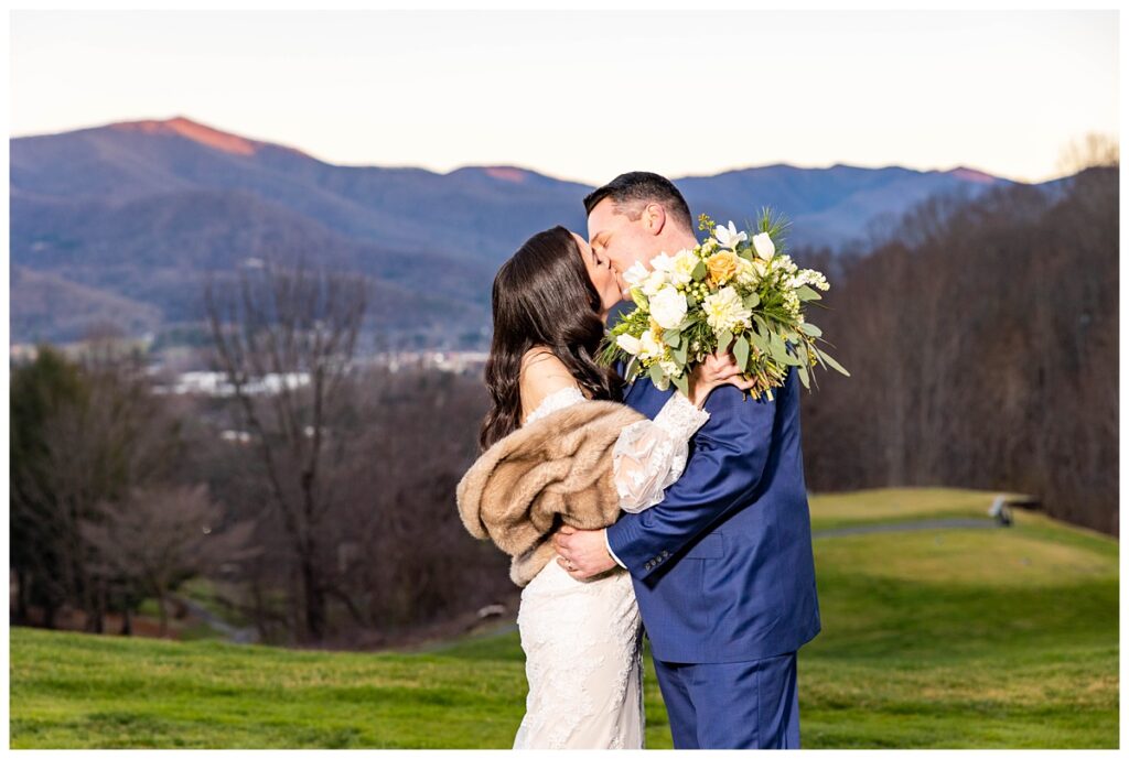 bride and groom kiss for outdoor portrait with mountains in the background