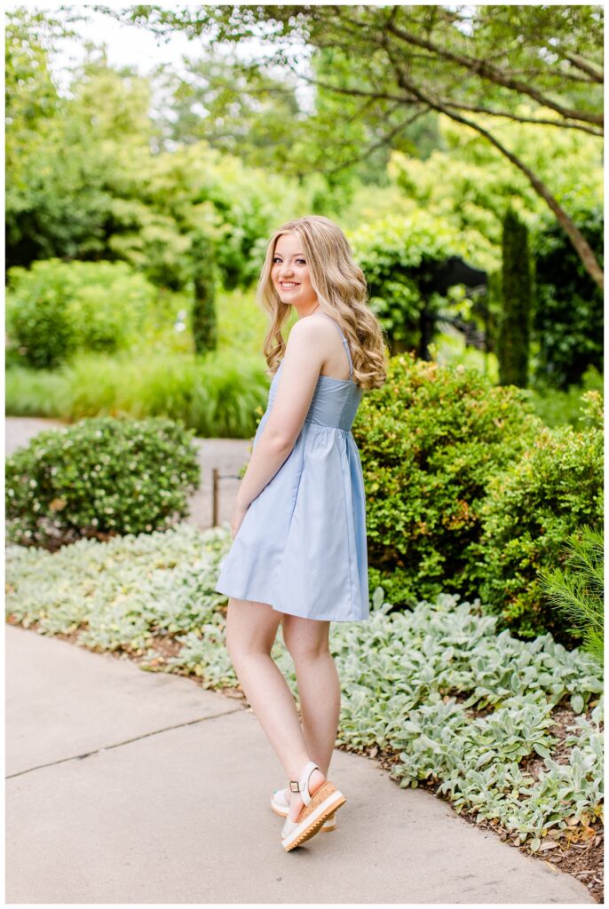 blonde girl in blue dress poses for NC Arboretum senior portraits